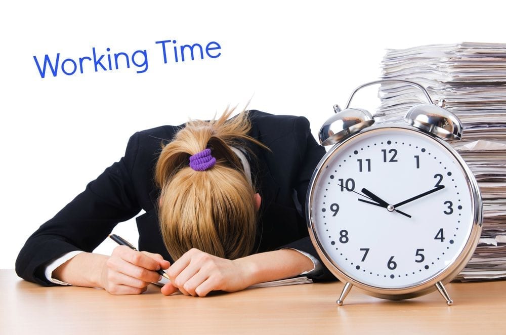 Large clock on a desk with a female head bowed resting on the table