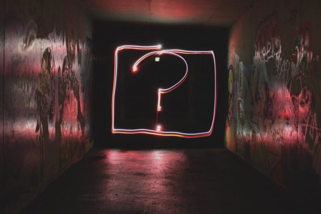 A neon sign of a question mark underground