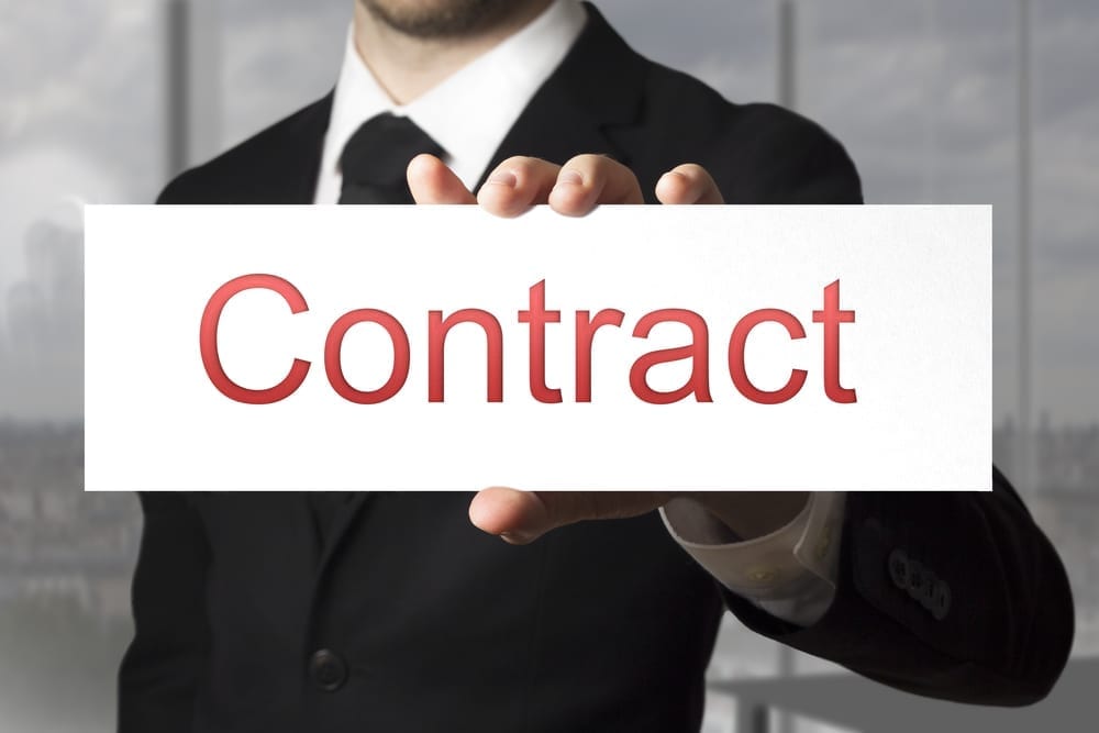 A business person holding a sign that reads "Contract"