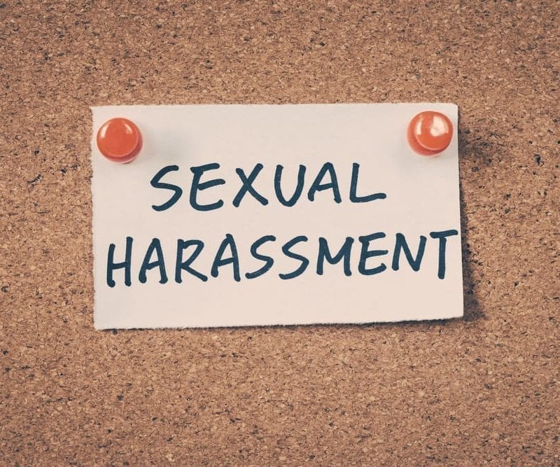 A piece of paper on a cork board reading "Sexual Harassment"