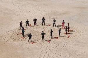 A circle of lifeguards training on a beach