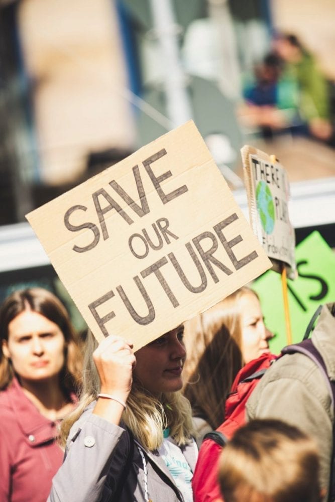 A person holding a sign with the words "Save our future" in amongst a protest