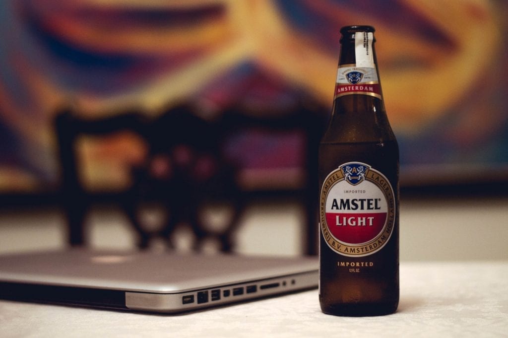 A bottle of Amstel Light beer next to a laptop