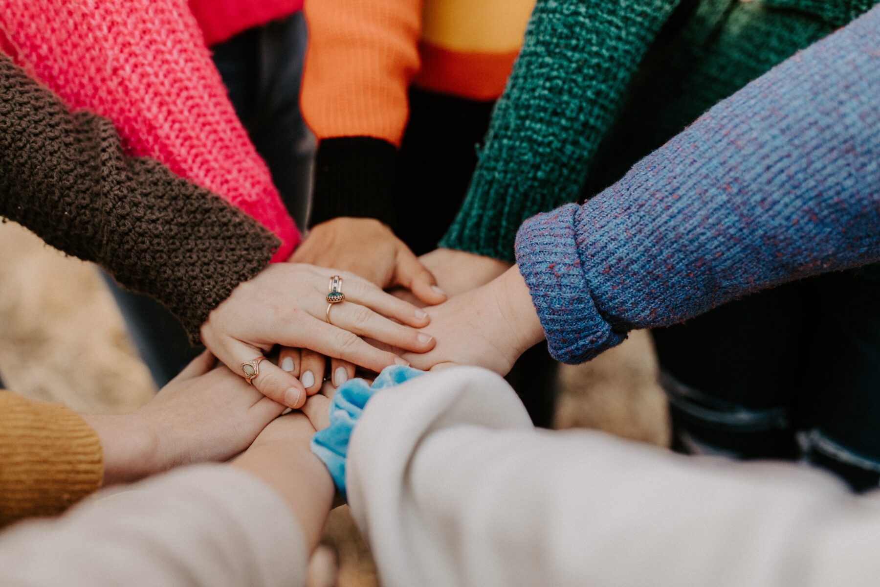 A circle of people with their hands together in the middle