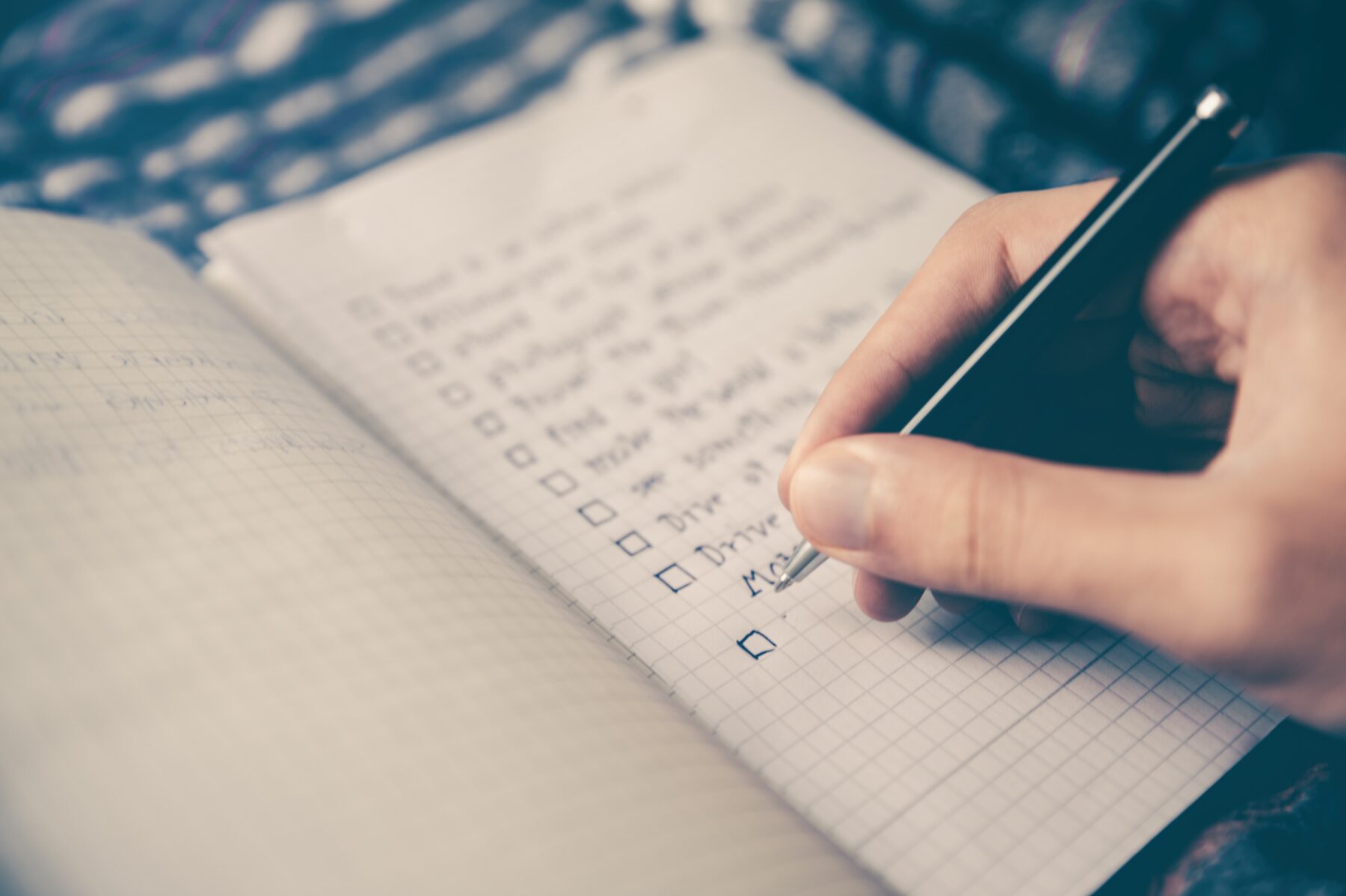 A person composing a checklist of tasks to do in a notebook