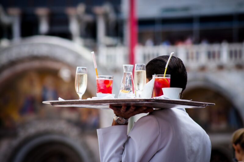 A drinks waiter carrying a tray of cocktails