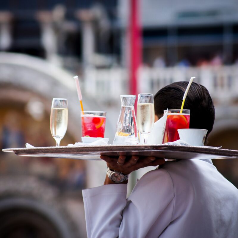 A drinks waiter carrying a tray of cocktails