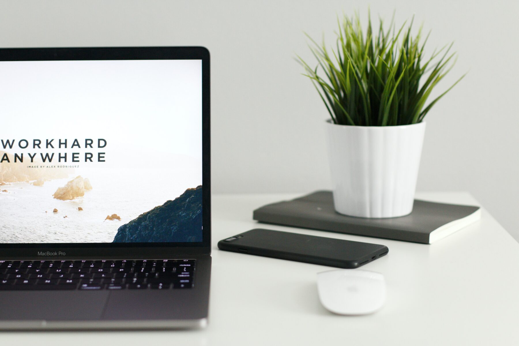 A laptop on a work desk with the words "Work hard anywhere" on screen