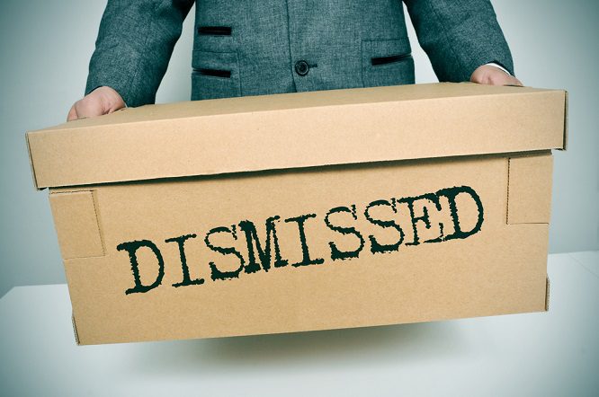 A person carrying a cardboard box with the word "Dismissed" written on it