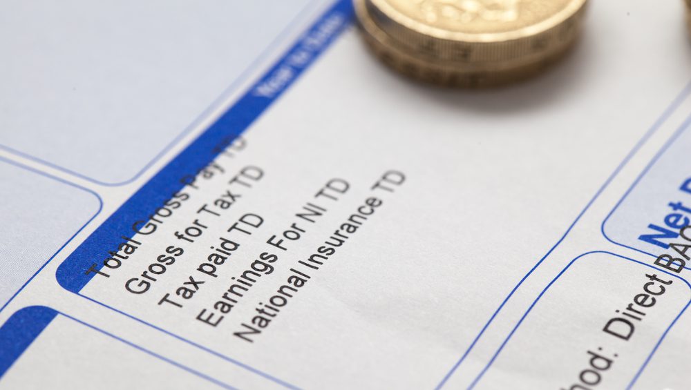wage slip with a pound coin on
