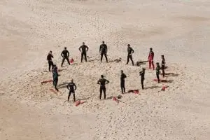 A circle of lifeguards training on a beach