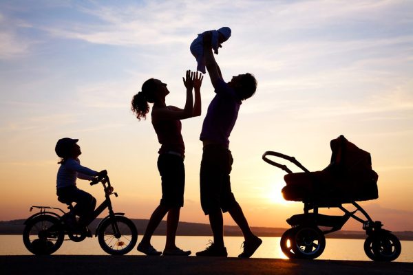 Sunset with parents baby and a pushchair as a black silhouette