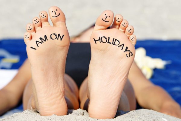 Pair of feet with I am on holiday written on the soles