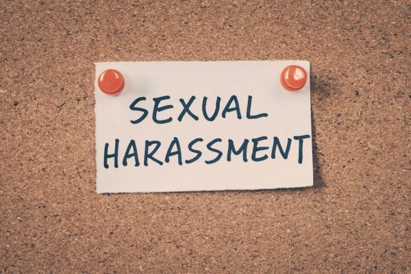 A piece of paper on a cork board reading "Sexual Harassment"